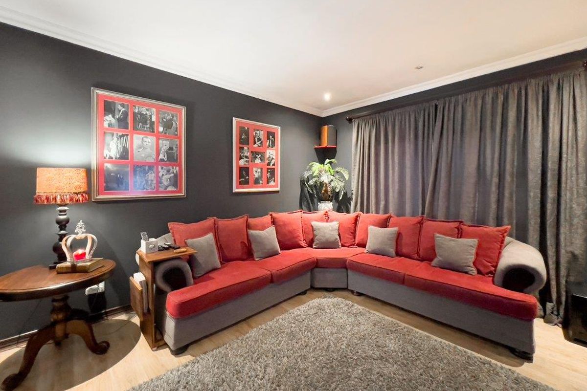 A cozy living room featuring dark accent walls, recessed downlighting, and light-toned flooring, creating a comfortable and inviting atmosphere.