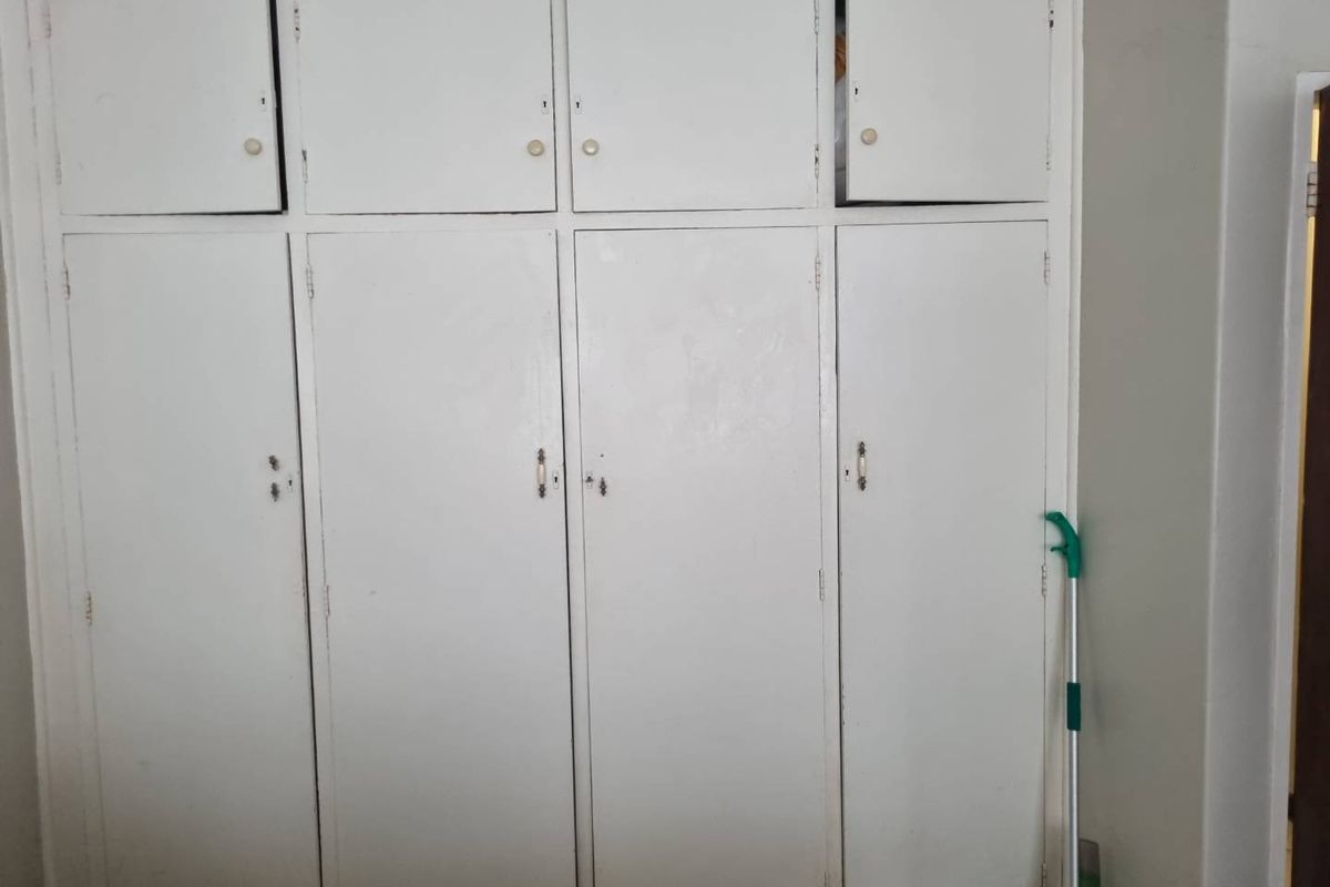 A set of built-in bedroom cupboards featuring multiple storage compartments with painted white doors and traditional hardware.