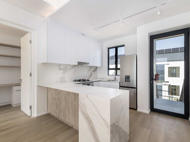 Modern kitchen featuring marble-look stone countertops, built-in cabinetry, gas hob, and integrated pantry, with direct access to a balcony.
