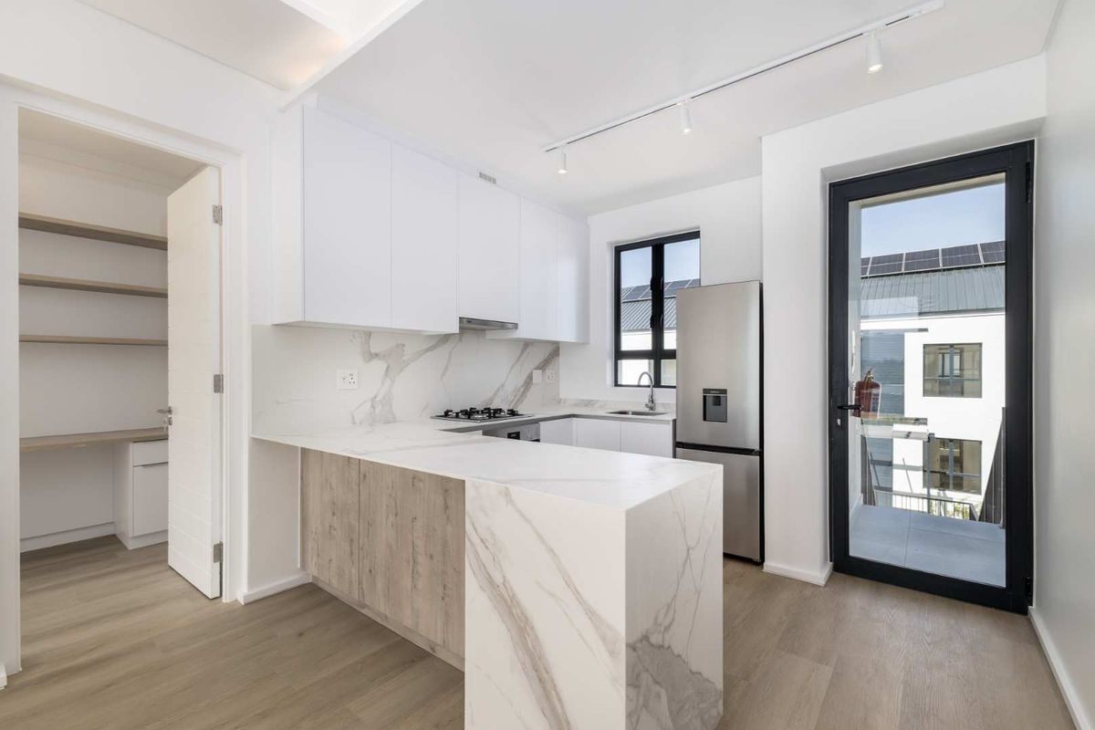 Modern kitchen featuring marble-look stone countertops, built-in cabinetry, gas hob, and integrated pantry, with direct access to a balcony.
