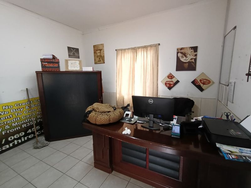 A functional office space featuring tiled flooring, a wall-mounted whiteboard, and neutral wall finishes, suitable for a professional work environment.