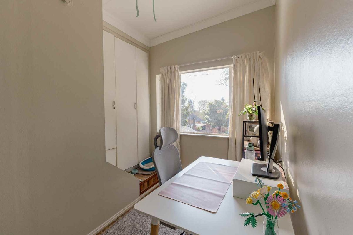 A compact bedroom featuring built-in cupboards, neutral wall finishes, and a window providing natural light.