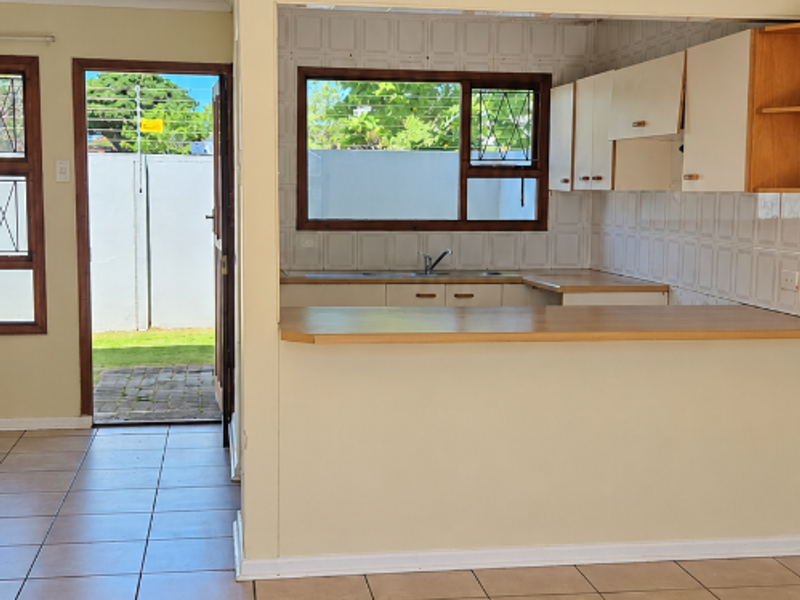 Open plan living area featuring tiled flooring and a functional kitchen with breakfast bar, leading directly to an outdoor patio area.