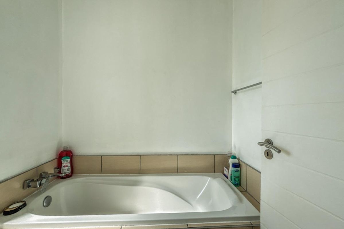 A functional bathroom featuring a built-in bathtub with tiled surround and a modern lever-handle door.
