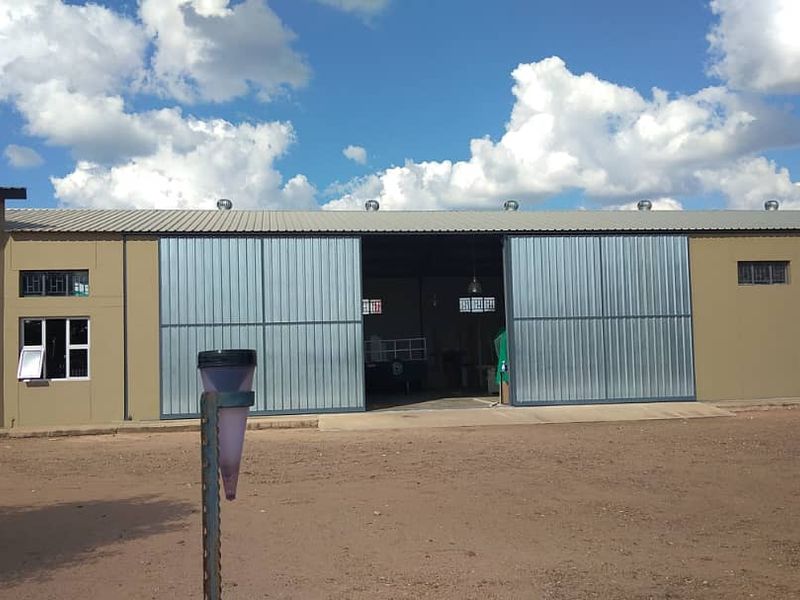 Industrial warehouse exterior featuring large corrugated metal sliding doors, roof ventilation turbines, and a concrete apron entrance.