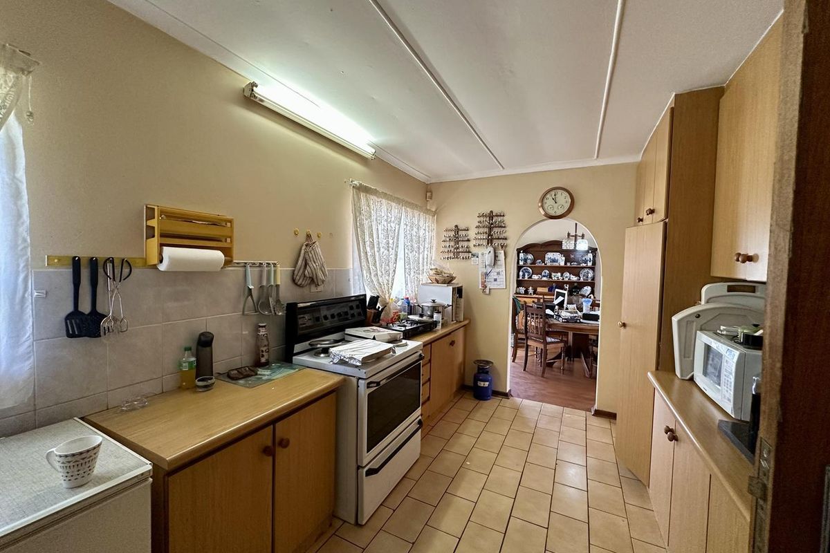 A functional kitchen featuring wood-finish cabinetry, tiled flooring, and a freestanding stove, with an arched doorway leading to the adjacent dining area.