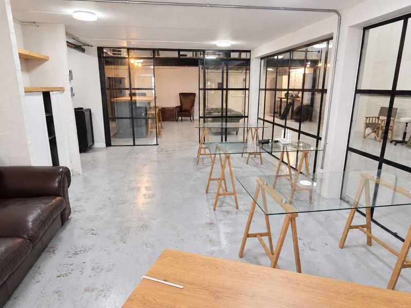 Spacious open-plan industrial office area featuring polished concrete floors, high ceilings with exposed conduit, and modern steel-framed glass partitioning.