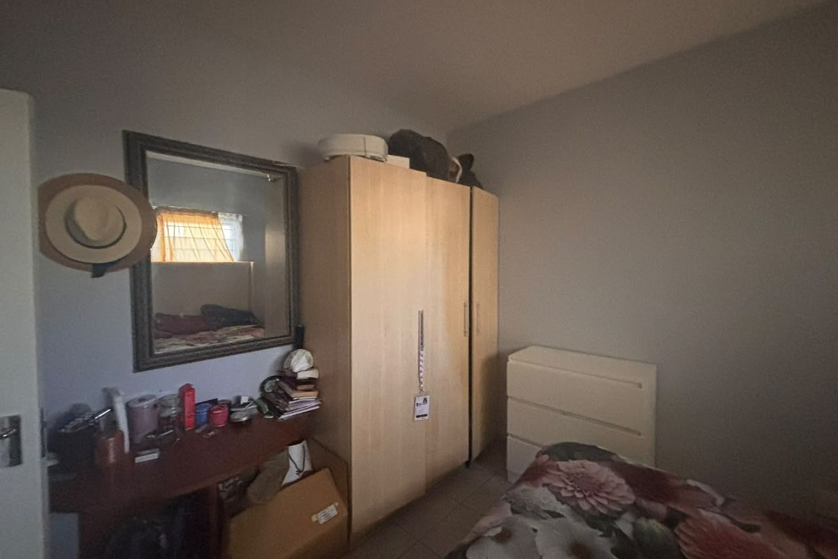 A bedroom featuring a built-in wardrobe and tiled flooring, offering functional storage space within the apartment.
