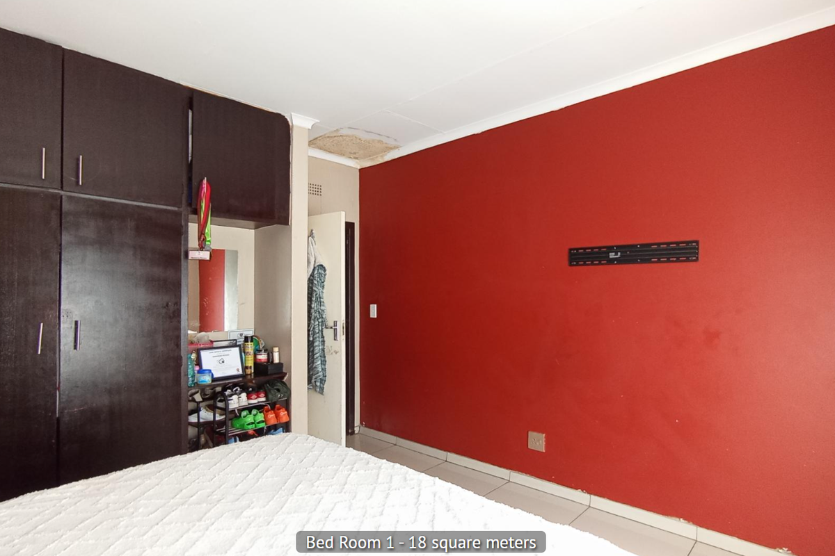 Bedroom featuring built-in dark wood cabinetry and a prominent red accent wall, with visible ceiling damage requiring repair.