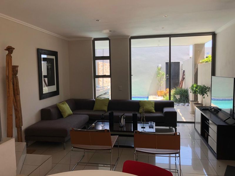 Modern living room featuring large sliding glass doors that provide seamless access to the outdoor patio and pool area.