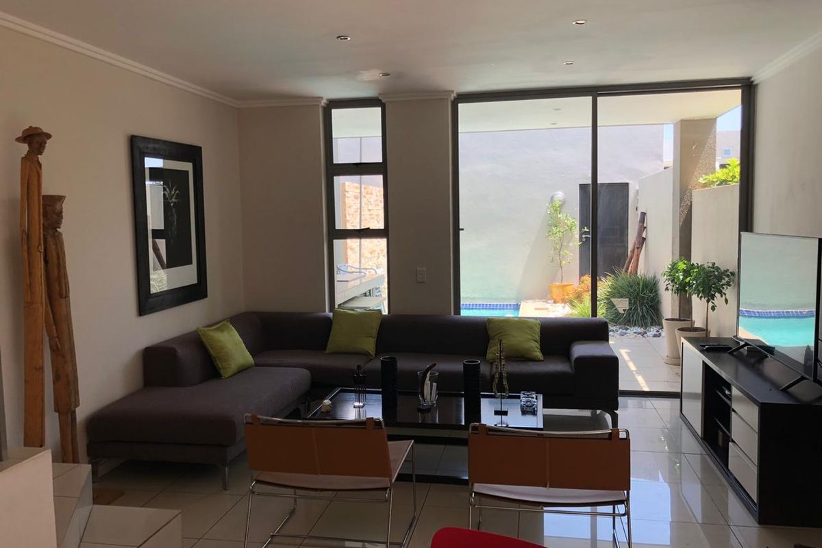 Modern living room featuring large sliding glass doors that provide seamless access to the outdoor patio and pool area.