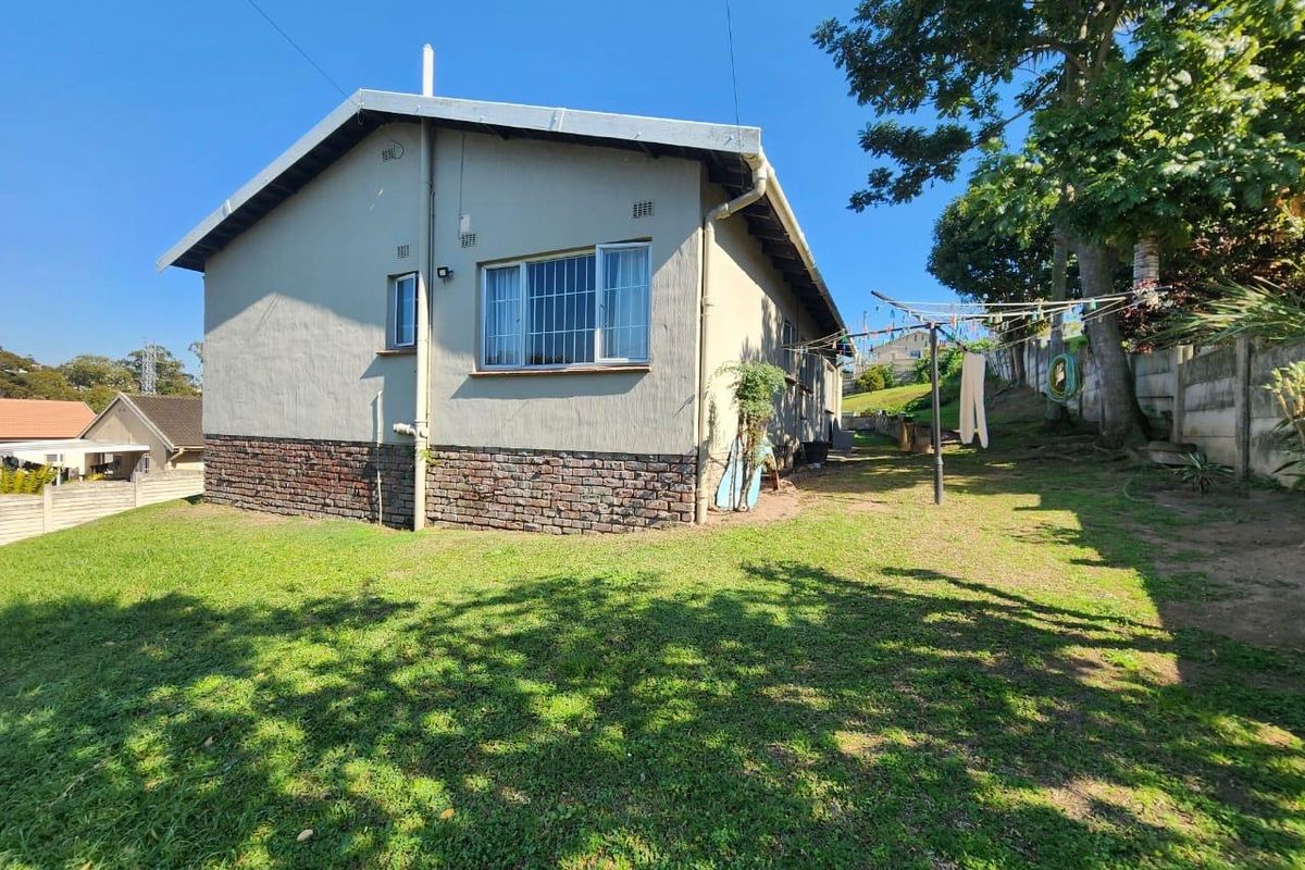 Rear view of the house showing the garden area, brick base detailing, and security bars on the windows.