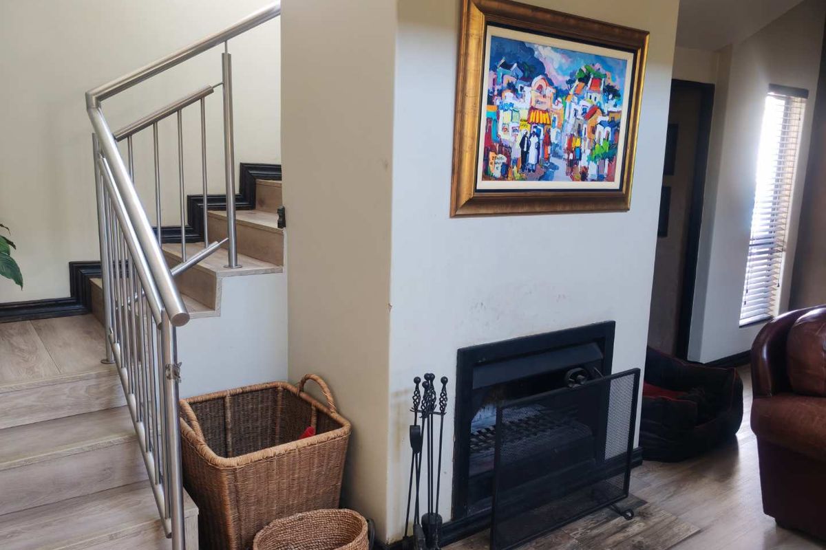 Living area featuring a built-in fireplace and a staircase with a modern stainless steel railing and tiled steps.