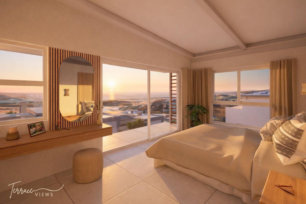 A modern bedroom featuring large sliding glass doors that open to a balcony with expansive coastal sunset views.