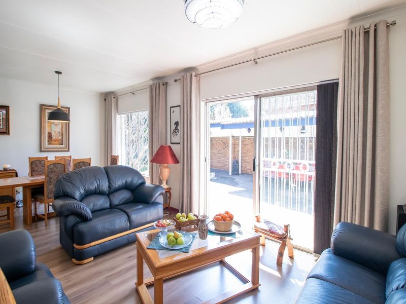 Bright open-plan living and dining area featuring laminate flooring and large sliding glass doors providing direct access to the rear patio.