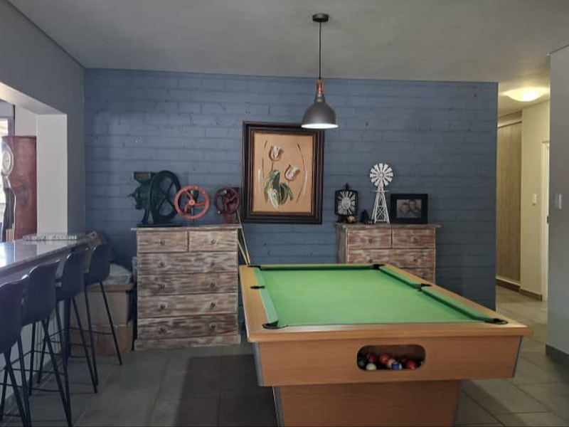 Spacious living area featuring an exposed brick feature wall, tiled flooring, and a built-in breakfast bar, offering a versatile space for entertainment.