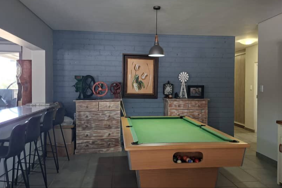 Spacious living area featuring an exposed brick feature wall, tiled flooring, and a built-in breakfast bar, offering a versatile space for entertainment.