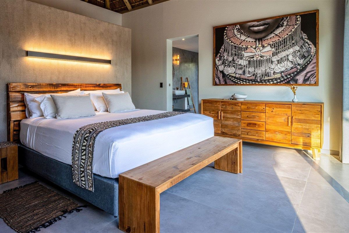 Spacious bedroom featuring modern tiled flooring, textured accent wall with integrated lighting, and direct access to an en-suite bathroom.