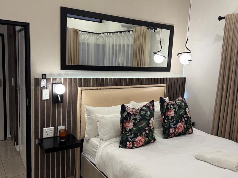 A well-maintained bedroom featuring tiled flooring, a modern built-in headboard with integrated lighting, and neutral wall finishes.