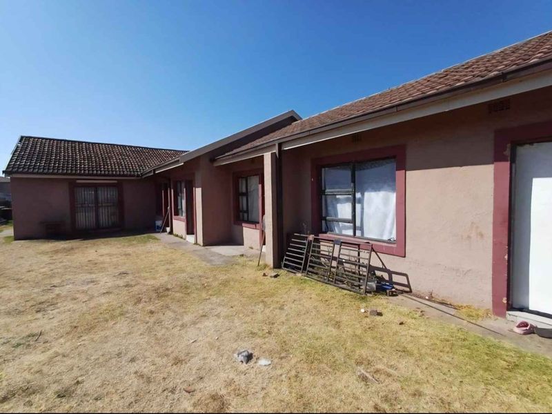 Rear view of the house showing the exterior facade, tiled roof, and surrounding yard area.
