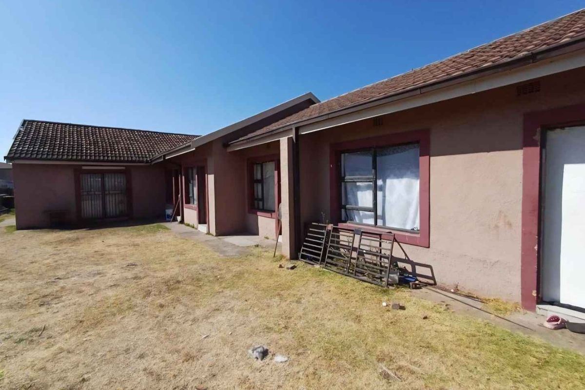 Rear view of the house showing the exterior facade, tiled roof, and surrounding yard area.