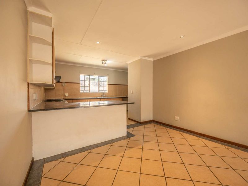 Open-plan kitchen and living area featuring tiled flooring, granite countertops, and built-in cabinetry, offering a functional and versatile space.