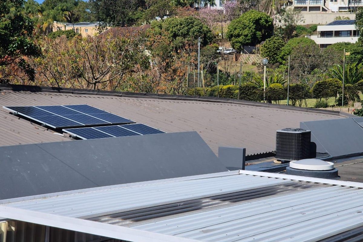 Elevated view of the property roof featuring installed solar panels, an air conditioning condenser unit, and a skylight.