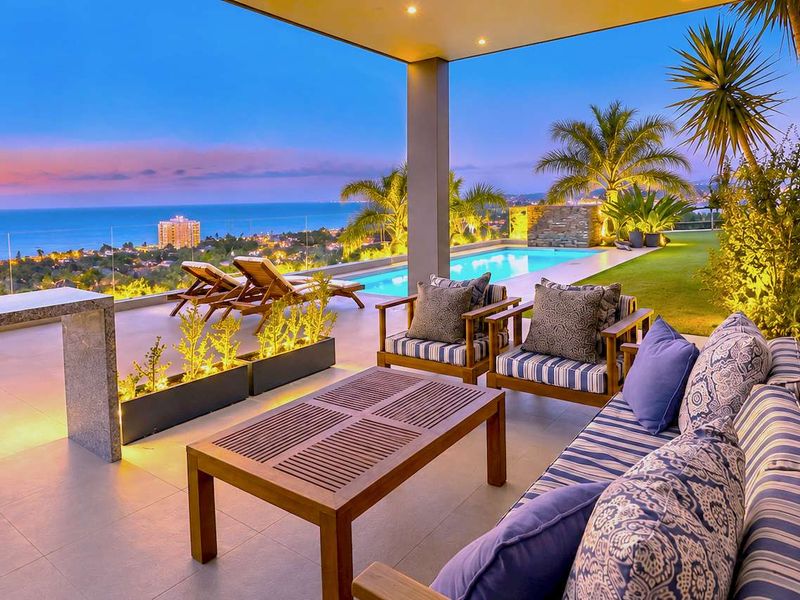 Spacious covered patio featuring a swimming pool, glass balustrades, and panoramic ocean views, perfect for outdoor entertaining.