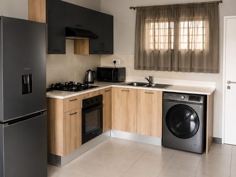 Modern kitchen featuring light wood-tone cabinetry, contrasting dark upper cabinets, gas hob, built-in oven, and integrated washing machine with neutral tiled flooring.