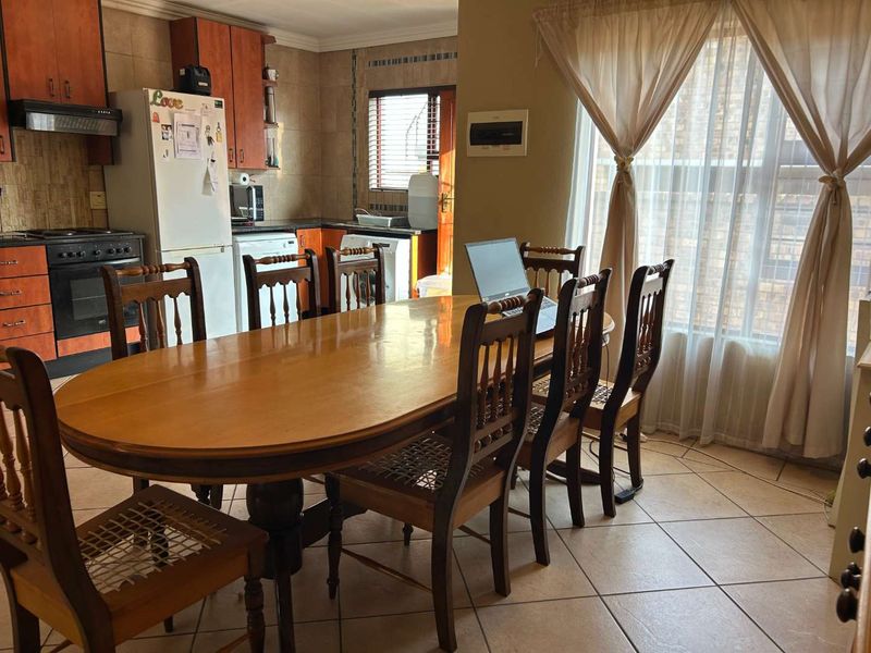Open-plan kitchen and dining area featuring tiled flooring, wooden cabinetry, and integrated cooking appliances, providing a functional space for daily living.