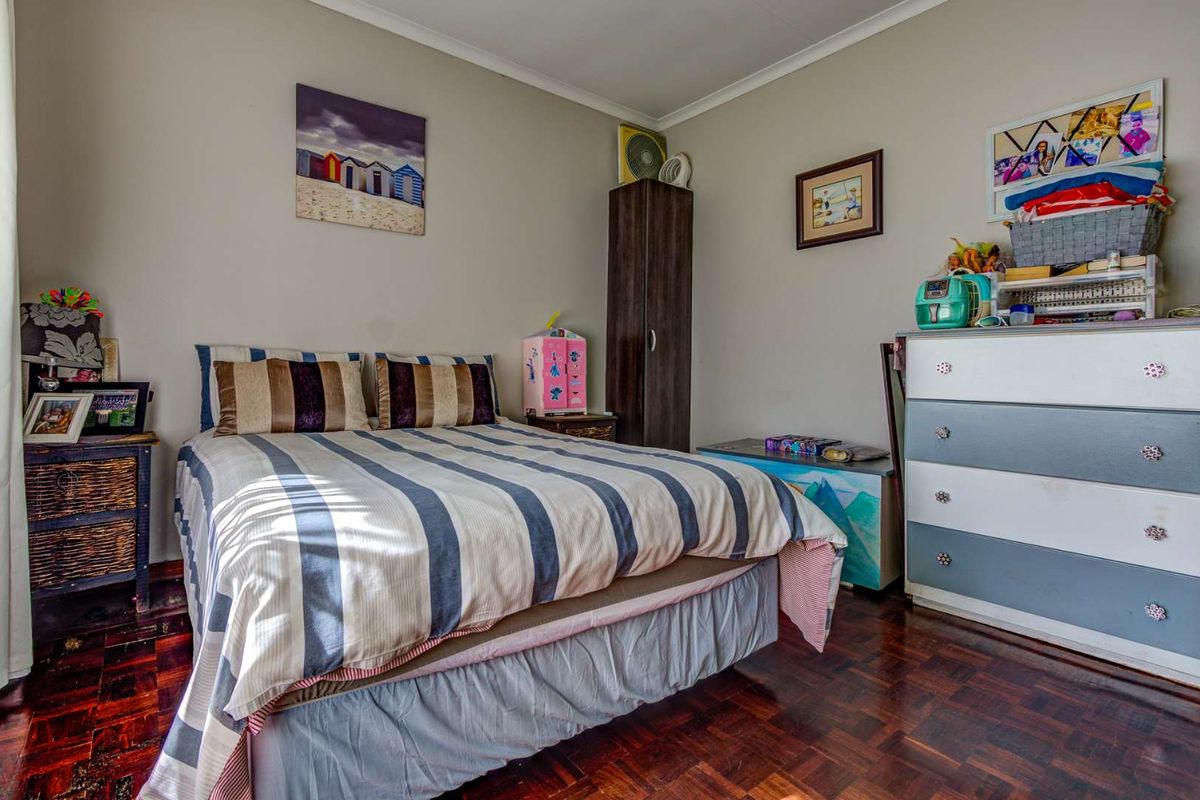 A bedroom featuring dark parquet flooring and neutral wall finishes, providing a functional space for rest.