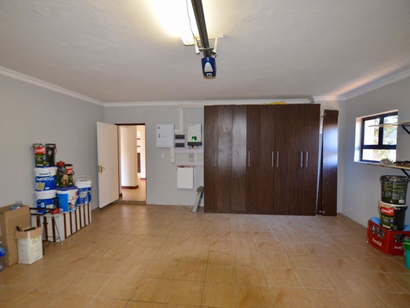 Spacious garage featuring tiled flooring, built-in storage cupboards, and an installed inverter system, providing functional utility and storage space.