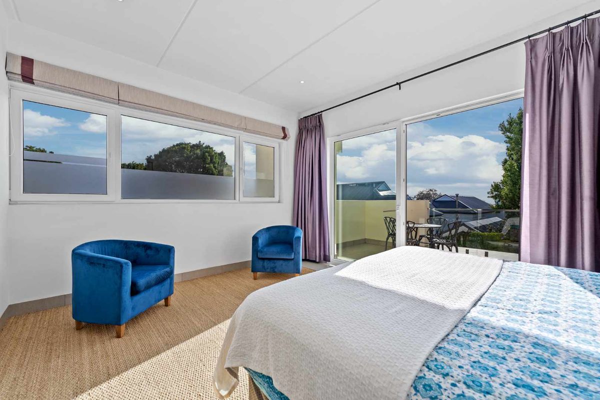 Spacious bedroom featuring large windows and sliding glass doors that open onto a private balcony with scenic views.