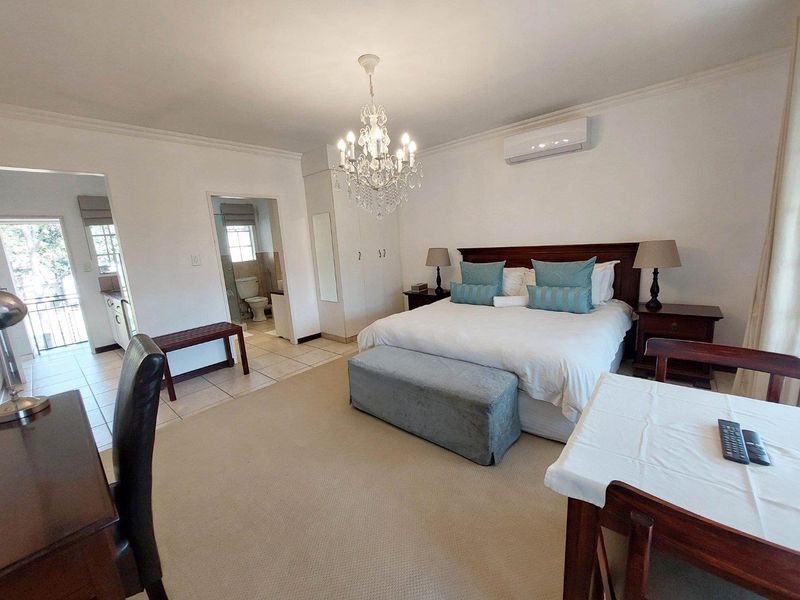 Spacious bedroom featuring neutral carpeting, built-in cupboards, a split-system air conditioner, and direct access to an en-suite bathroom.