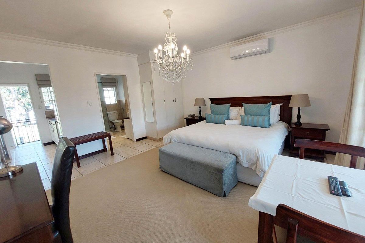 Spacious bedroom featuring neutral carpeting, built-in cupboards, a split-system air conditioner, and direct access to an en-suite bathroom.