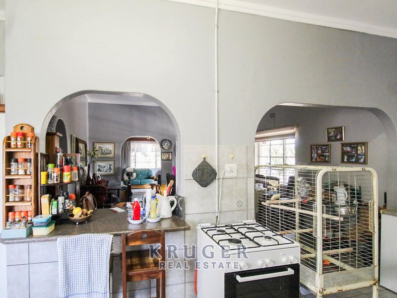 Kitchen area featuring a gas stove, tiled splashback, and breakfast bar, with arched openings leading into the adjacent living spaces.