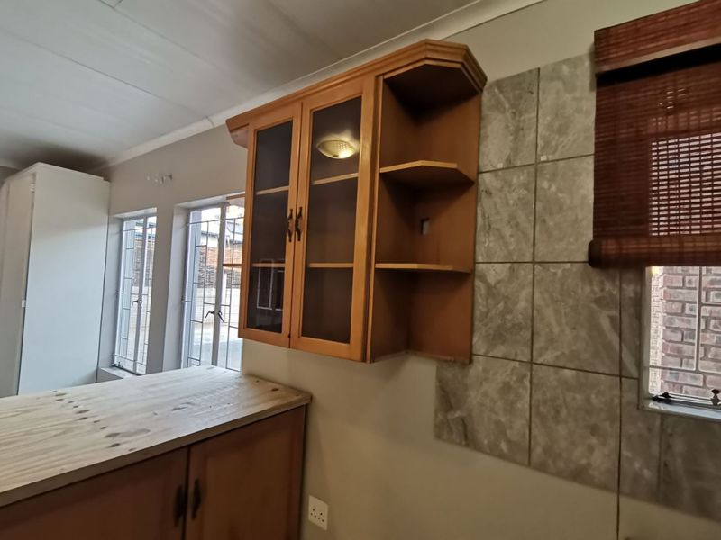 A kitchen area featuring wooden cabinetry, a tiled splashback, and a wooden countertop, offering a functional space ready for modern updates.