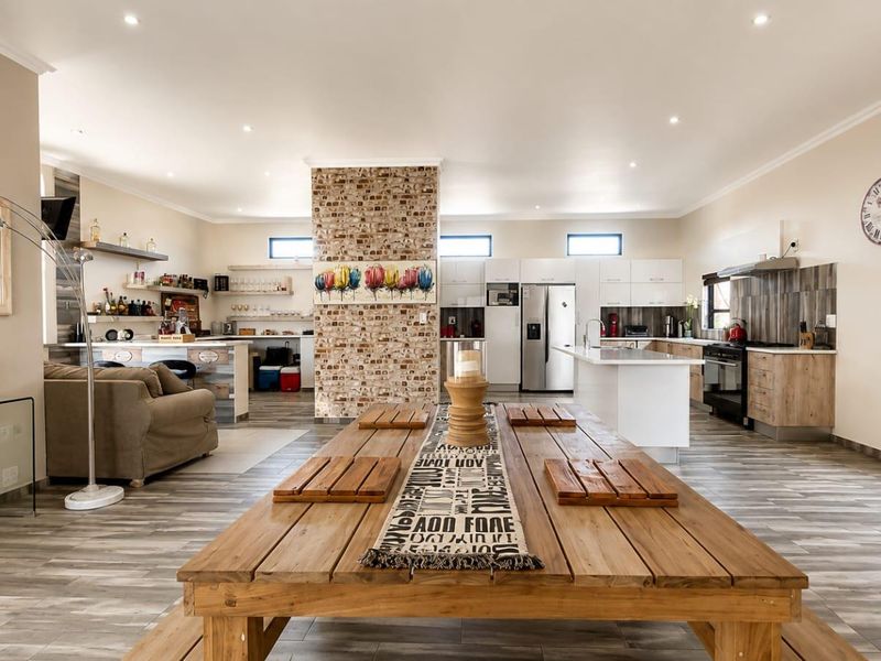 Spacious open-plan living and kitchen area featuring a central exposed brick pillar, modern cabinetry, kitchen island, and contemporary tiled flooring throughout.