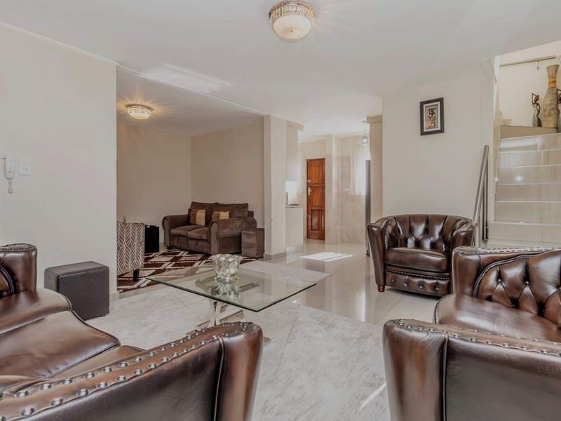 Spacious living area featuring tiled flooring, a central staircase, and neutral wall finishes, providing a comfortable and well-lit open-plan layout.