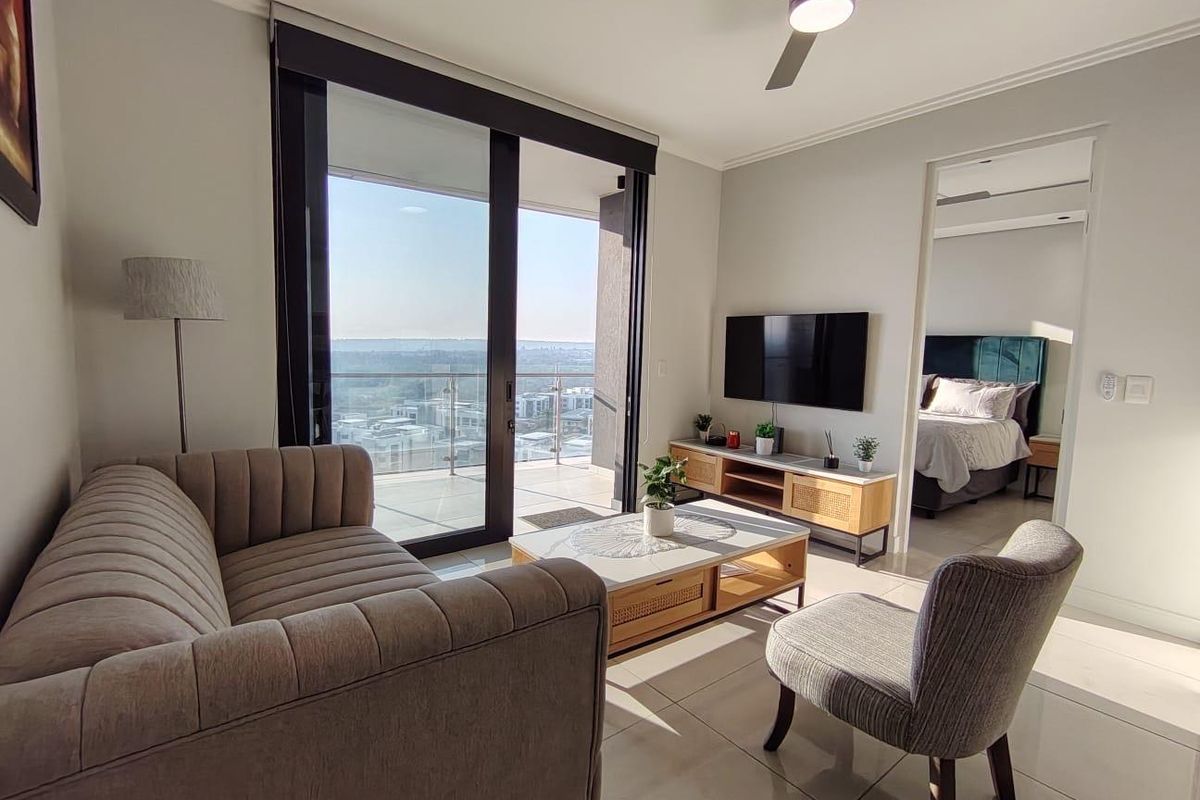 Modern living room featuring tiled floors, a ceiling fan, and large sliding glass doors leading to a balcony with expansive views.