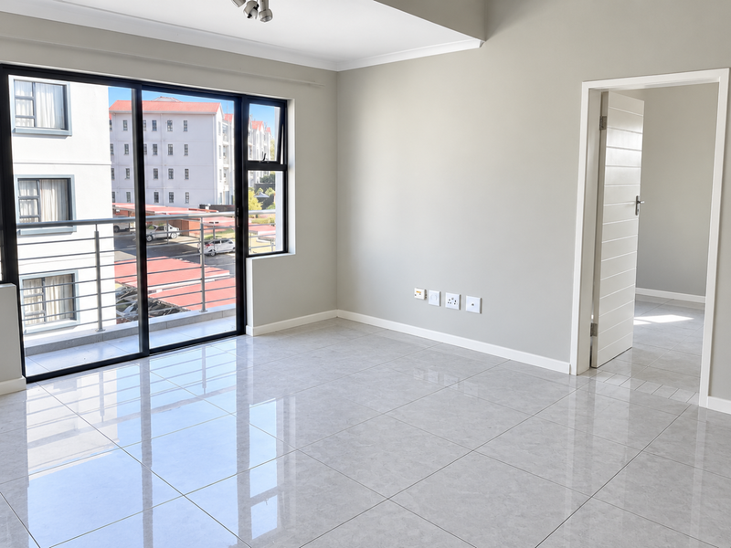 A bright, empty living area featuring polished tile flooring, neutral walls, and a sliding glass door leading to a balcony.