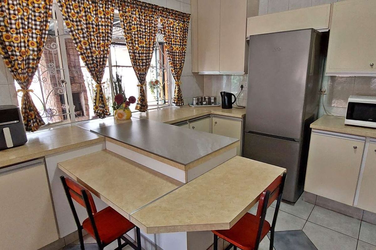 A functional kitchen featuring laminate countertops, built-in cabinetry, tiled walls, and a central breakfast bar area.