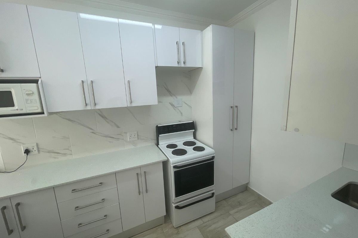 Modern kitchen featuring white cabinetry, stone countertops, marble-look splashback, and a built-in electric stove with integrated microwave.