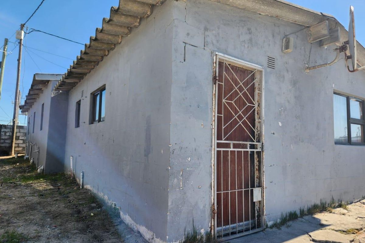 Exterior view of the rear building facade featuring a security gate, aluminium window frames, and a corrugated roof structure.