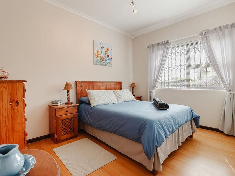 A well-maintained bedroom featuring laminate flooring, built-in wardrobe storage, and a window fitted with security bars for added peace of mind.