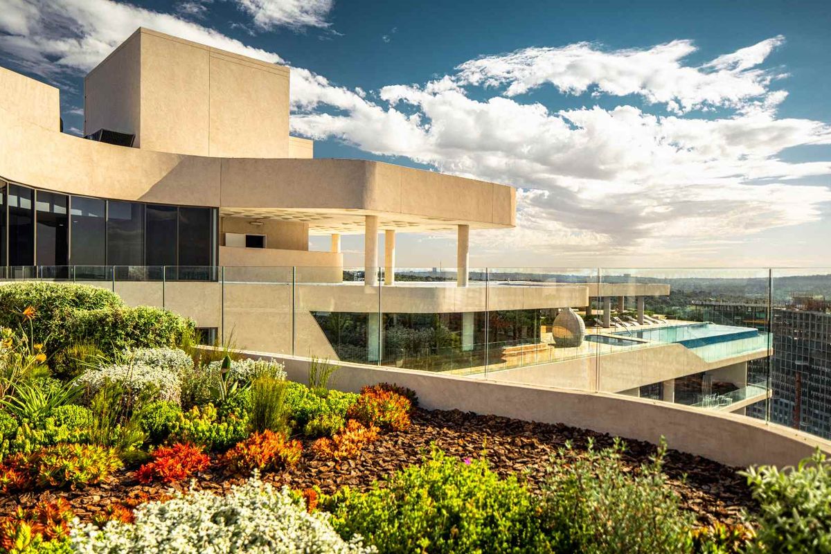 A stunning penthouse exterior featuring expansive terraces, glass balustrades, and a private infinity pool overlooking the city skyline.