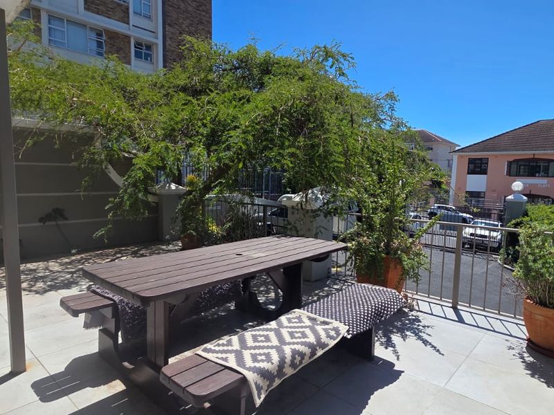 A spacious outdoor patio area featuring tiled flooring and a metal balustrade, providing a functional space for outdoor relaxation.