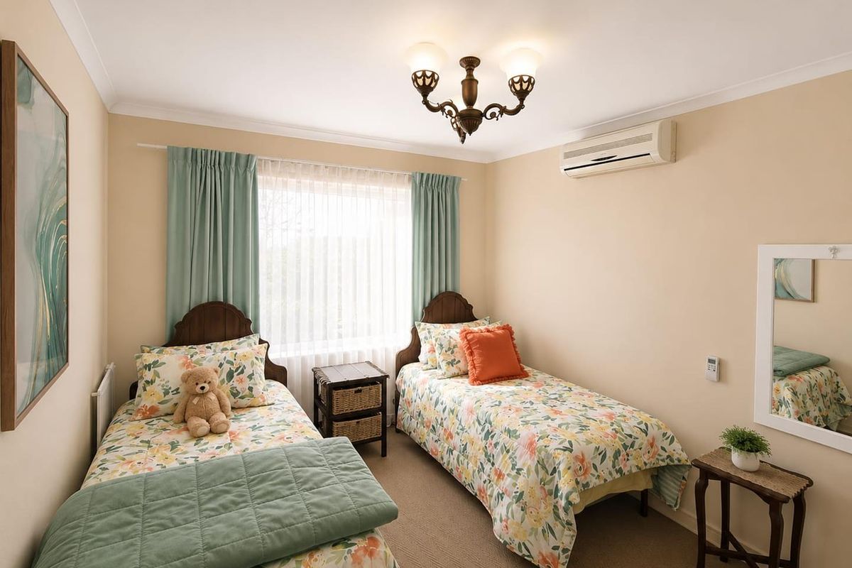 A well-maintained bedroom featuring neutral wall tones, carpet flooring, and a wall-mounted split-system air conditioner.