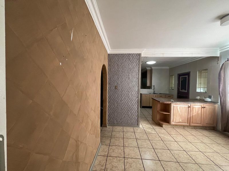 Open plan living area featuring tiled floors, crown molding, and a kitchen with built-in cabinetry and an island, offering a functional layout.