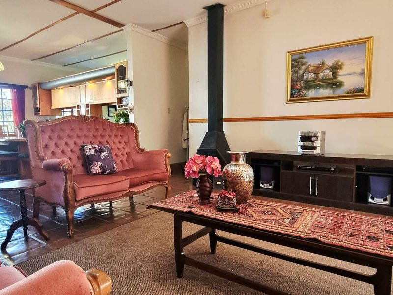 Spacious open-plan living and dining area featuring a central freestanding fireplace, tiled flooring, and exposed beam ceilings, flowing into the adjacent kitchen space.
